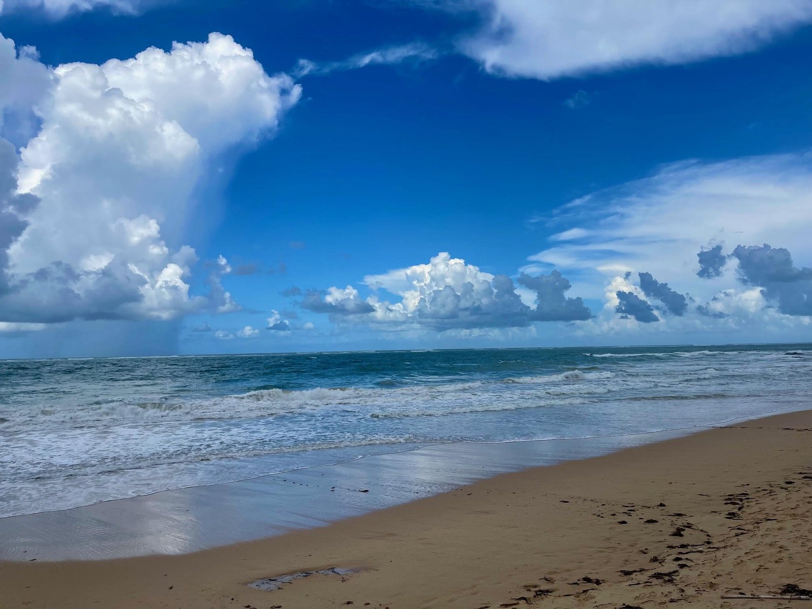 Ocean Park Beach in San Juan Puerto Rico with turquoise Caribbean waves, white sand shoreline, and dramatic blue sky — half a block from Acacia Boutique Hotel